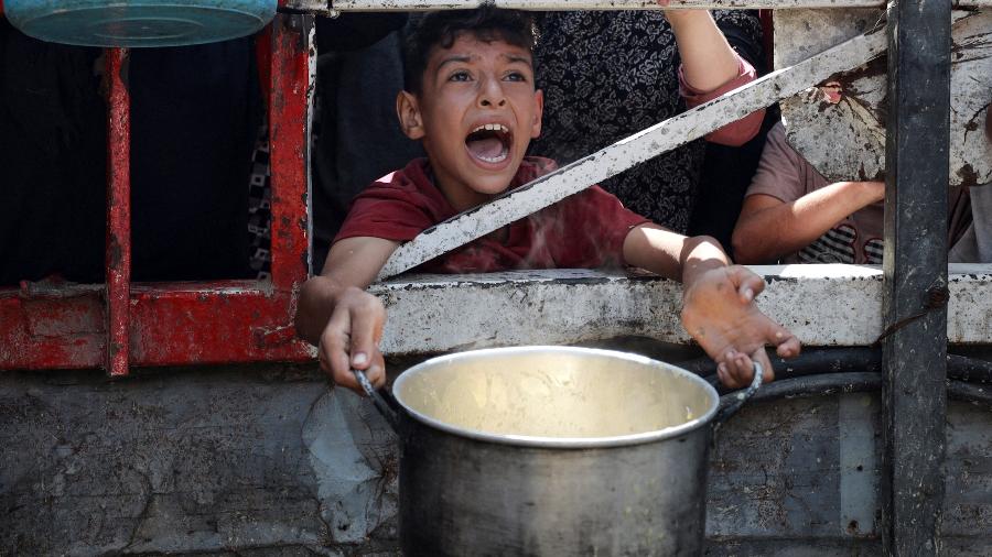 Um palestino reage enquanto espera para receber comida de uma cozinha de caridade, em meio a uma crise de fome, na Cidade de Gaza