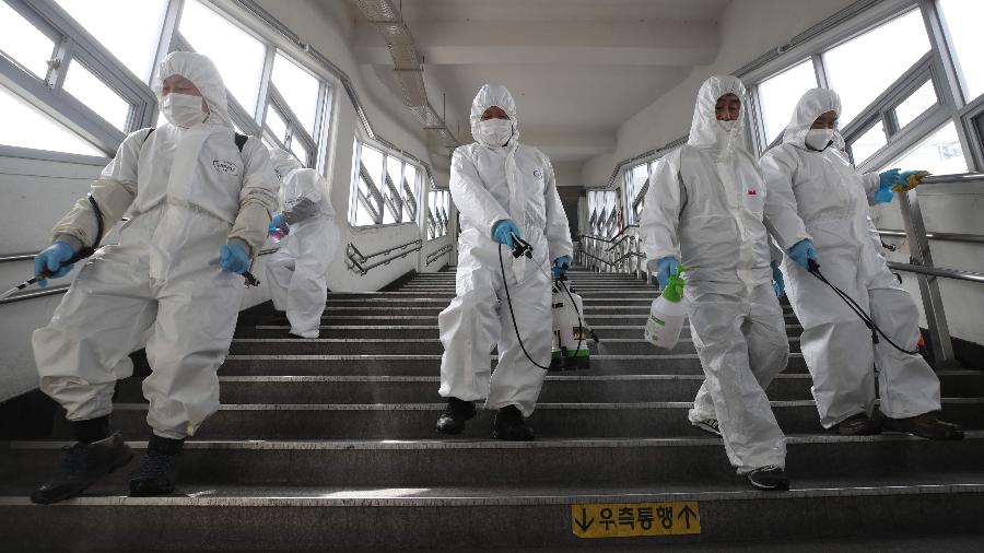 Funcionários desinfetam uma estação de metrô em Seul, na Coreia do Sul, em mais uma ação para evitar o aumento de transmissões do novo coronavírus no país - YONHAP / AFP