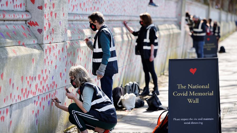 29.mar.2021 - Corações vermelhos são pintados na parede do dique no lado sul do Rio Tâmisa em memória daqueles que perderam suas vidas para covid-19 em Londres  - Tolga Akmen/AFP