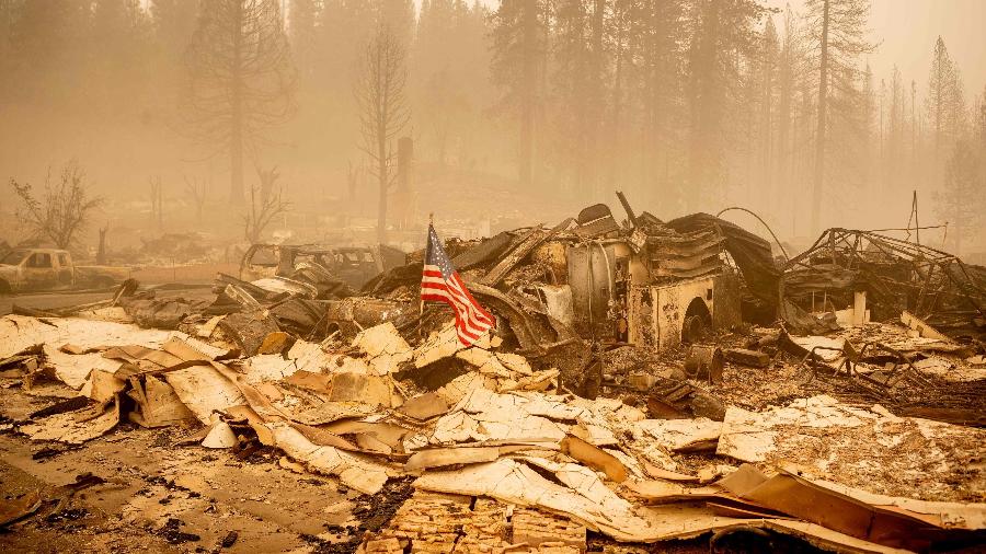 7.ago.2021 - Bandeira dos EUA é colocada em meio a veículos destruídos pelo fogo em Greenville, na Califórnia - Josh Edelson/AFP