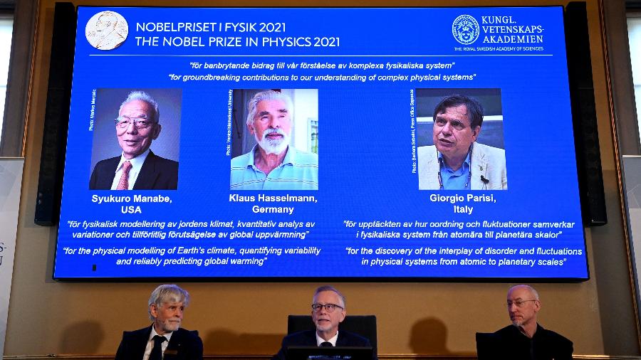 Tela mostra os vencedores do prêmio Nobel de Física de 2021: Syukuro Manabe, Klaus Hasselmann e Giorgio Parisi - Jonathan Nackstrand/AFP