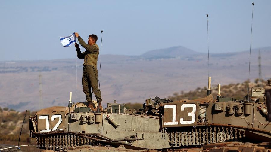 Soldado israelense instala bandeira de Israel em tanque de guerra durante treinamento militar na fronteira com o Líbano 