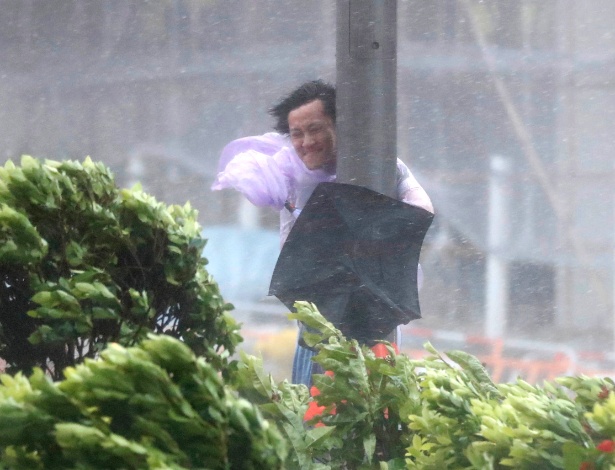 Homem se agarra a poste em passagem de tufão por Hong Kong nesta quarta-feira - Tyrone Siu/Reuters