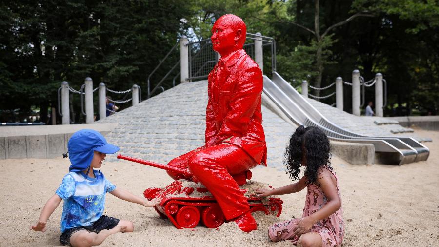Crianças brincando com uma estátua de Vladimir Putin em Nova York, EUA. A obra é do artista francês James Colomina - ANDREW KELLY/REUTERS