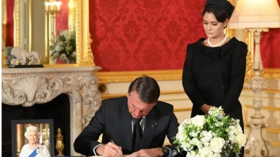 Jair Bolsonaro (PL), ao lado da primeira-dama Michelle Bolsonaro, assina o livro de condolências pela morte da rainha Elizabeth 2ª, em Londres - GETTY IMAGES