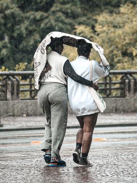 28.jan.2024 - Pedestres se protegem da chuva na região do Vale do Anhangabaú, centro de São Paulo