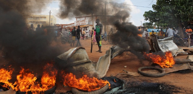 Manifestantes protestam ao lado de barricada em rua da capital de Burkina Fasso, Uagadugu no sábado (19)