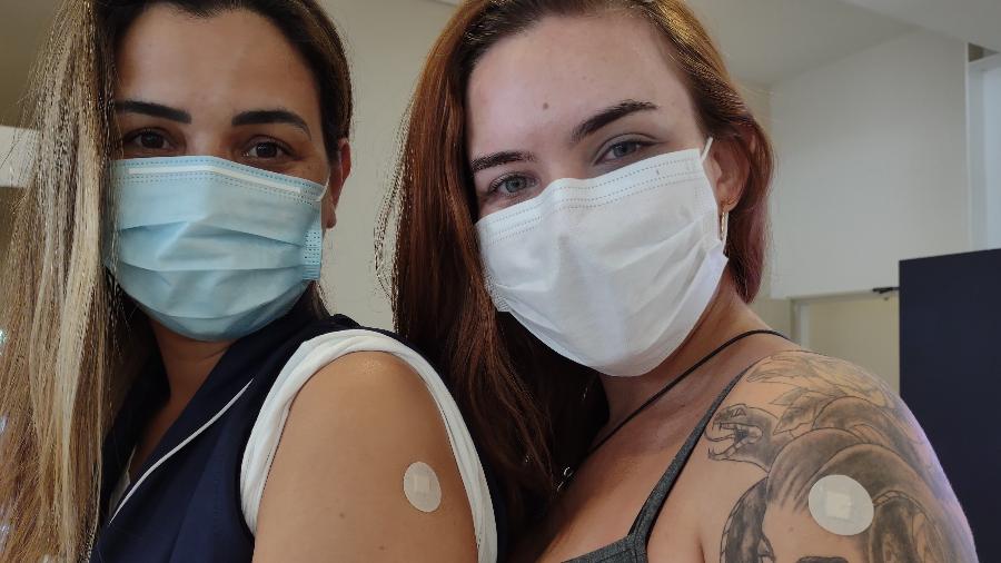 As enfermeiras Elaine Maria da Cunha, 34, e Carolina Vieira Rodrigues, 23, mostram curativo após tomarem vacina contra covid no Hospital das Clínicas, em São Paulo - Arthur Stabile/UOL