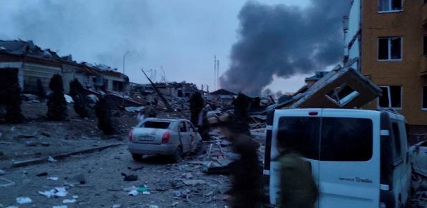 13.mar.2022 - Fumaça sobe em meio a prédios e veículos danificados após um ataque à base militar de Yavoriv
