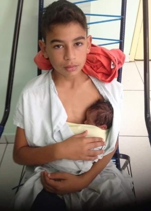 A imagem do menino segurando o irmãozinho recém-nascido no colo foi publicada na rede social - Reprodução/ Facebook