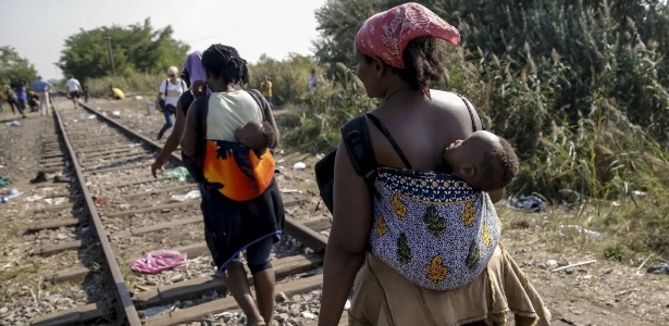 21.abr.2016 - Imigrantes carregam bebês em linha de trem na Sérvia, em direção à fronteira com a Hungria