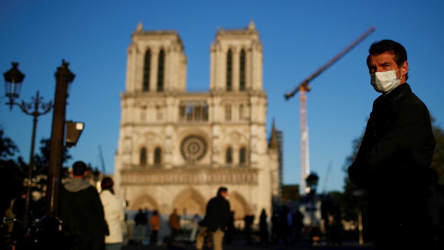 Homem usando uma máscara facial ouve o grande sino da Catedral de Notre-Dame de Paris tocando - GONZALO FUENTES/REUTERS