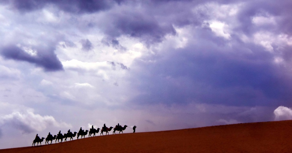 07.out.2015 - Turistas passeiam com camelos perto do Lago Shahu, em Ningxia, na China