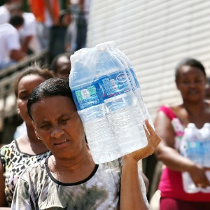 Após enfrentarem longa fila, mulheres carregam garrafas de água para retirar em Governador Valadares (MG) - Bruno Alencastro/Agência Rbs/Estadão Conteúdo