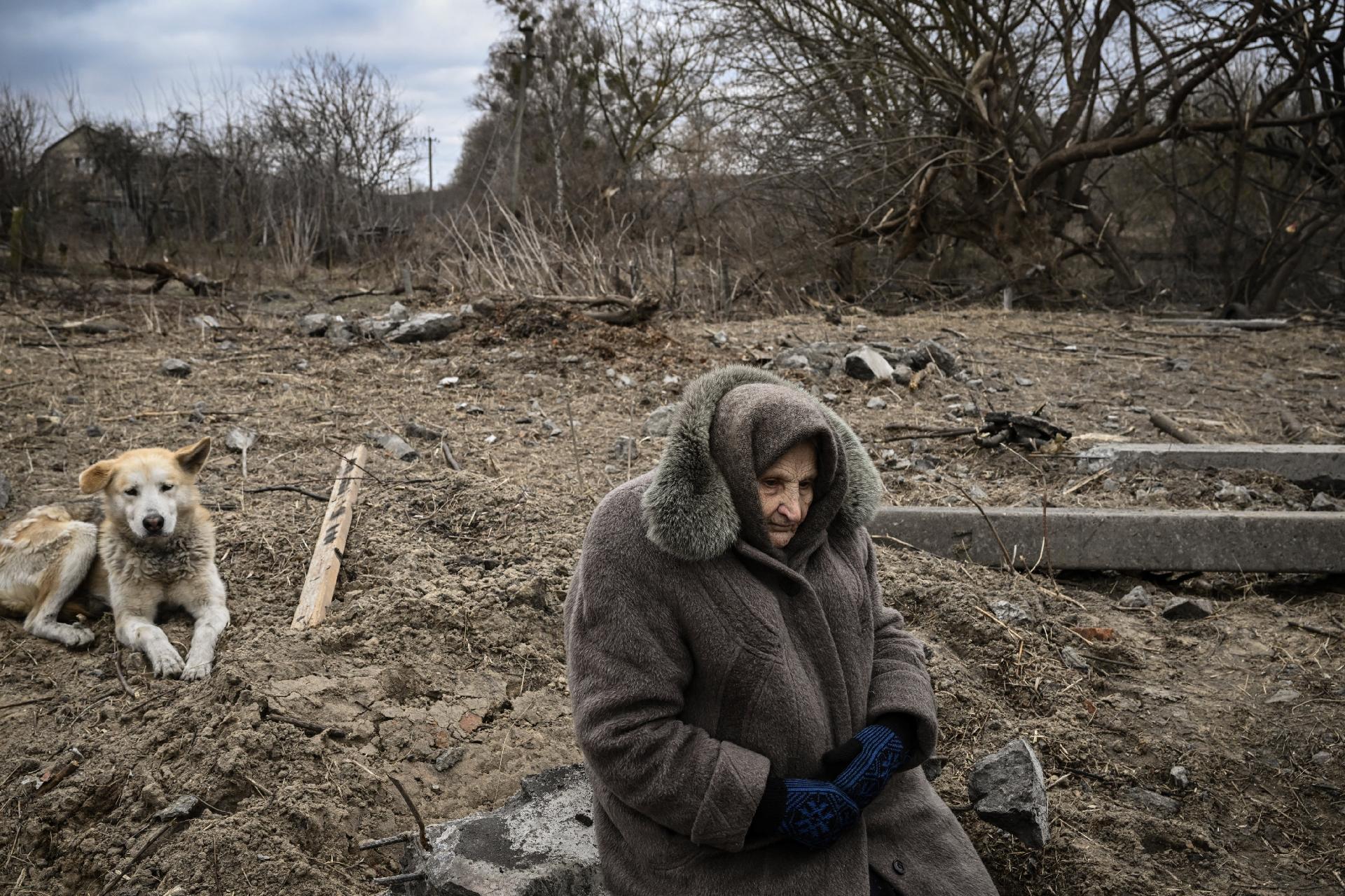 March 5, 2022 - A woman sits as people cross a destroyed bridge in the town of Irpin, northwest of Kiev - March 5, 2022 - Aris Messinis/AFP