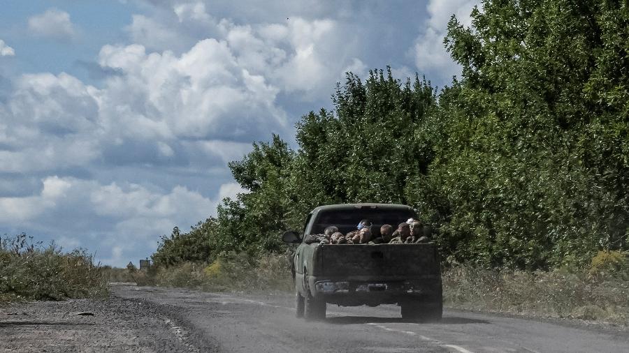 Soldados ucranianos viajam em um veículo militar com prisioneiros de guerra russos na caçamba do caminhão, em meio ao ataque da Rússia à Ucrânia