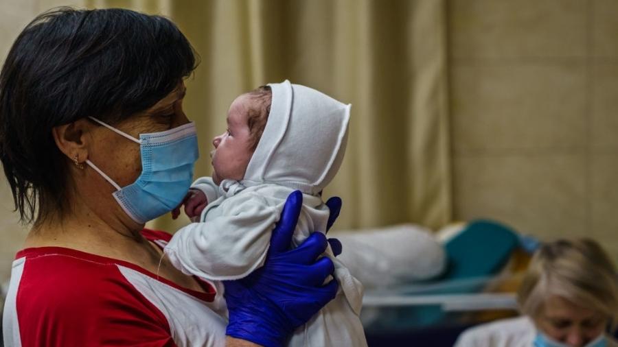 Uma enfermeira com um bebê no berçário subterrâneo de Kiev - GETTY IMAGES