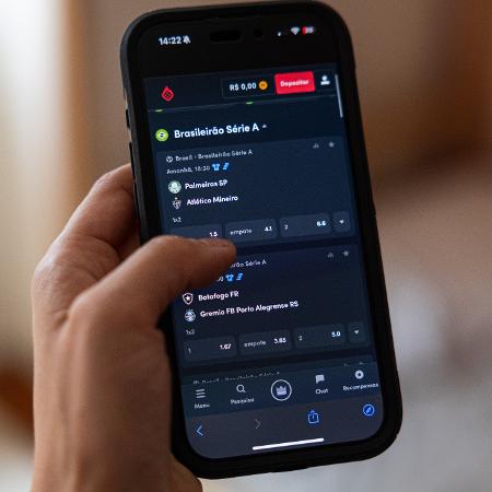 Pessoa segura celular com aplicativo de bets Pessoa segura celular com aplicativo de bets