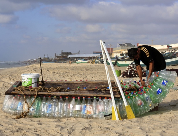 O pescador Abu Zeid realiza reparos em seu barco, feito de 700 garrafas plásticas - Said Khatib/AFP