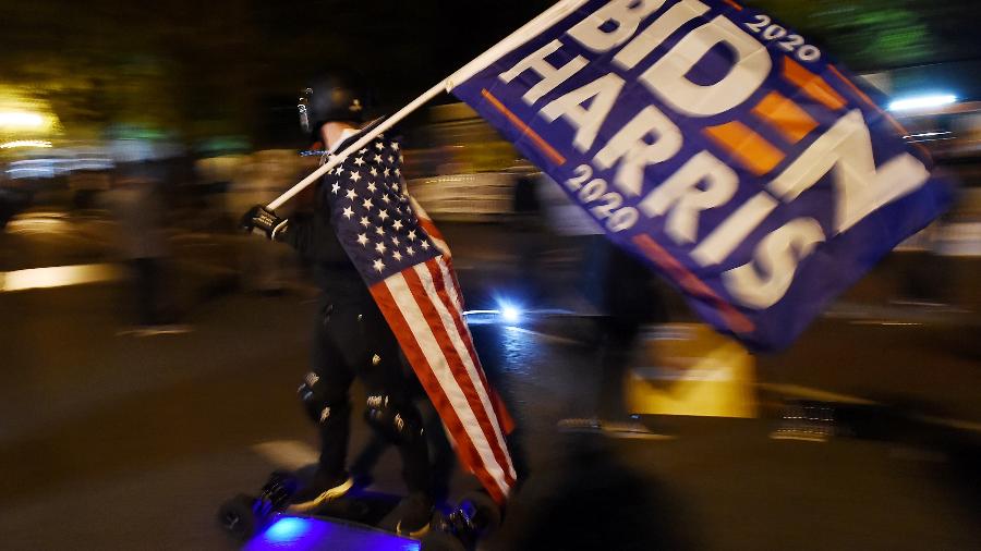 Apoiador do candidato democrata Joe Biden carrega bandeira em ato do movimento Black Lives Matter perto da Casa Branca, em Washington  - Olivier Douliery/AFP