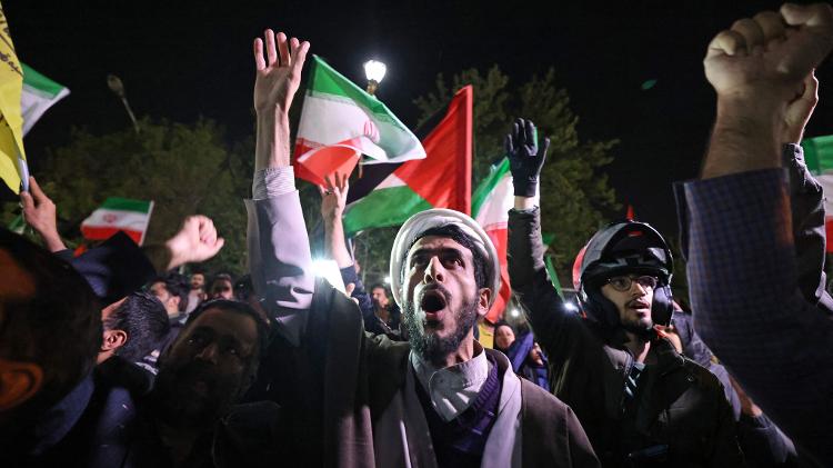 14.abr.2024 - Manifestantes agitam as bandeiras do Irã e da Palestina em frente à embaixada britânica em Teerã, captal do Irã