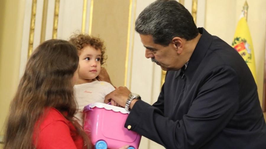 14.mai.2025 - Presidente venezuelano Nicolas Maduro brinca com a menina Maikelys Espinoza, que está nos braços de sua mãe, Yorely Bernal - ZURIMAC CAMPOS / Venezuelan Presidency / AFP