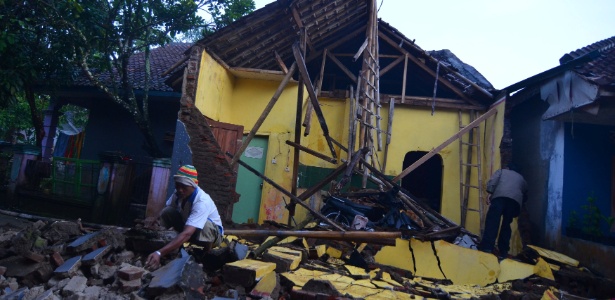 Homem limpa destroços de casa destruída por terremoto em Java, Indonésia - Adeng Bustomi/ Antara Foto via Reuters
