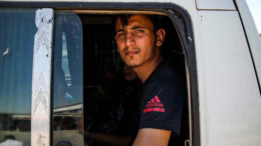 24.jul.2019 - Um refugiado sírio, entre os repentinamente deportados da Turquia, anda de ônibus em direção a áreas controladas pelos rebeldes da província de Aleppo - Aaref Watad/AFP