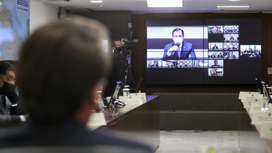 21/05/2020 - João Doria (na tela) se pronuncia durante videoconferência com o presidente Jair Bolsonaro (de costas) e outros governadores - Marcos Corrêa/PR/Divulgação