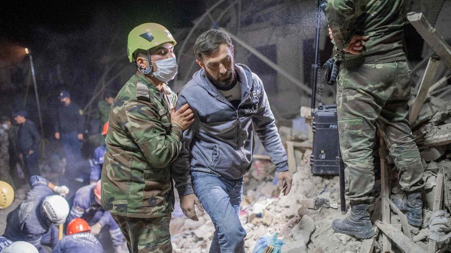 Socorrista ajuda morador na busca por parentes após míssil atingir área residencial no Azerbaijão - Bulent Kilic/AFP