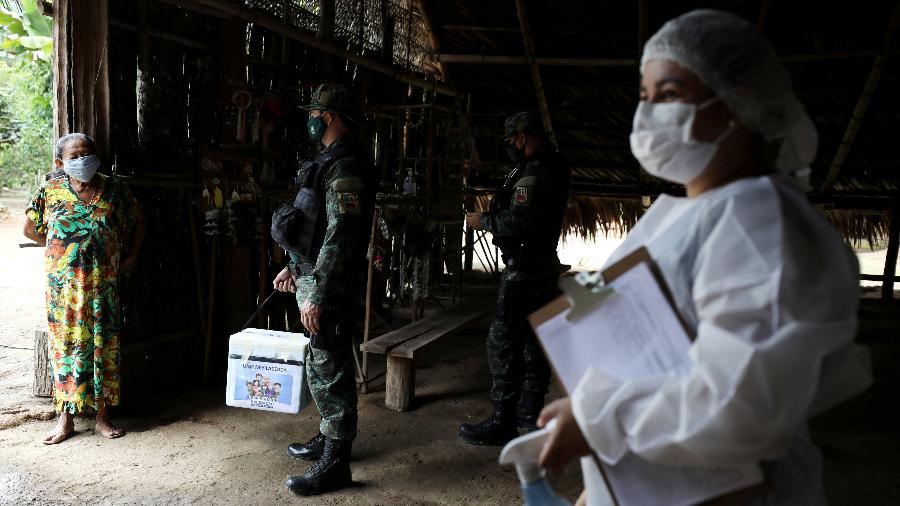 Profissional de saúde e policial militar conversam com indígena no Amazonas  - Bruno Kelly/Reuters