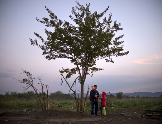 27.out.2015 - Refugiado descansa com seus filhos enquanto espera para entrar em acampamento para imigrantes perto de Gevgelija, na Macedônia