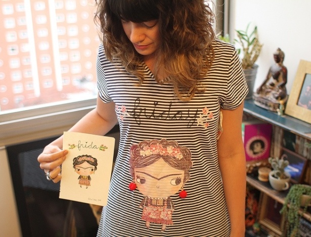 Júlia Lima segura sua ilustração e veste camiseta vendida nas Lojas Renner  - Reprodução