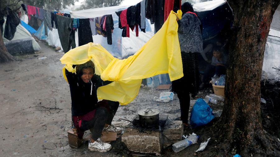13.dez.2019 - Menina tenta se proteger da chuva com um pedaço de lona plástica em um campo de refugiados na Grécia - Giorgos Moutafis/Reuters