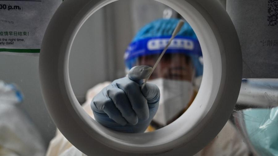 Um trabalhador da saúde faz teste de covid-19 em Xangai, na China - onde medidas restritivas foram aliviadas pelo governo após manifestações - HECTOR RETAMAL/AFP