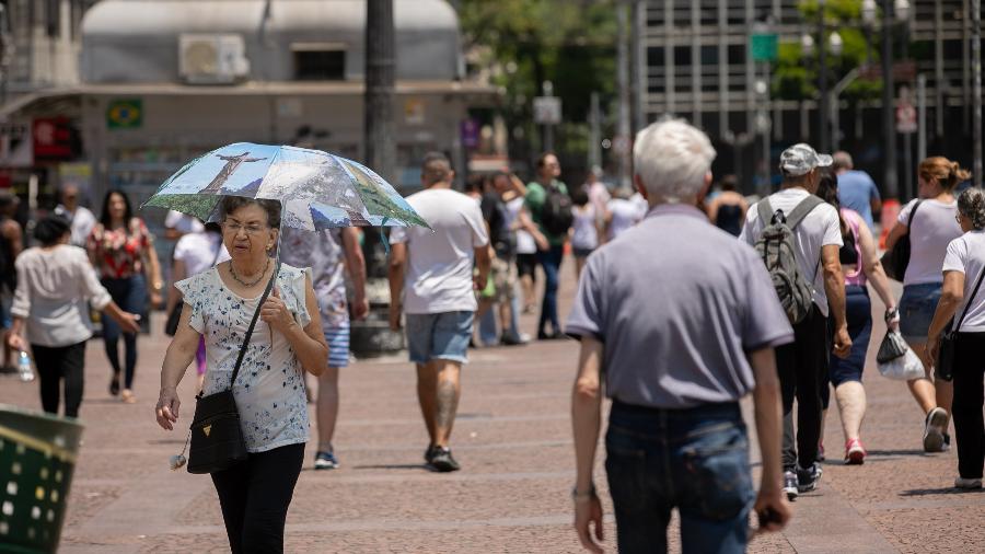 Pessoas caminham e se protegem do forte sol e calor na região central de Sao Paulo - Bruno Rocha - 2.fev.2024  - Agência Enquadrar/Agência O Globo
