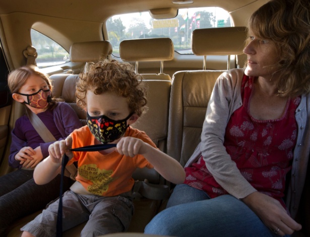 A partir da esquerda: Hannah e Alex Dawes usam máscaras para se proteger da poluição em Nova Déli. A mãe deles, Aurelia Driver, acompanha as crianças até a escola - Kuni Takahashi/The New York Times