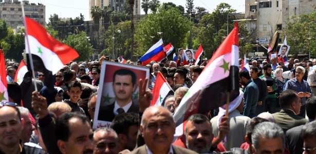 Manifestantes carregam bandeiras e retratos do presidente sírio - George Ourfalian/AFP Photo