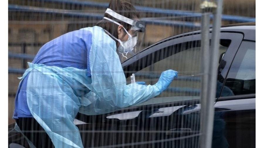 Profissional de saúde usa um cotonete para coleta de amostras pela janela do carro em um "drive-thru" de exames em Edimburgo - PA Media