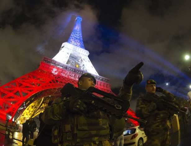 Segurança é reforçada na Torre Eiffel, em Paris, que está iluminada com as cores da bandeira francesa para homenagear as vítimas do ataques na cidade - Joel Saget/AFP