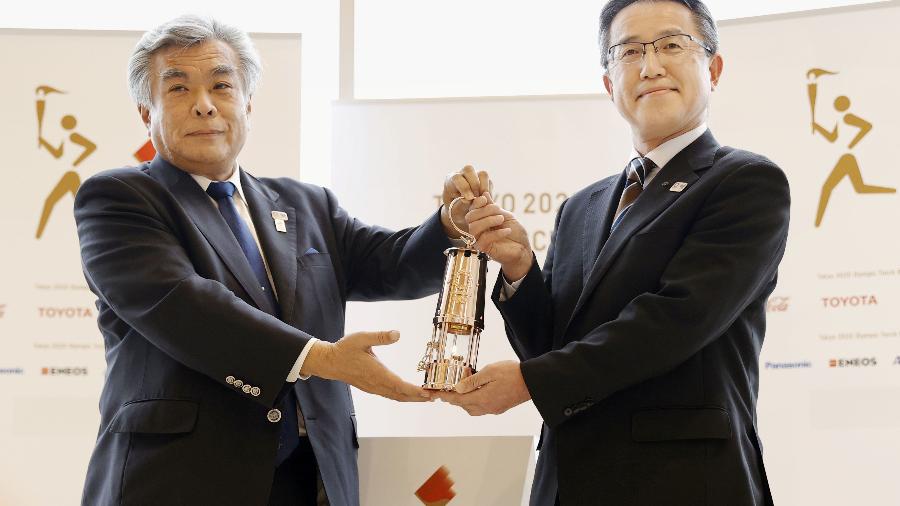 Chefe do gabinete de cultura e esporte de Fukushima, Makoto Noji, segura lanterna com chama olímpica - KYODO
