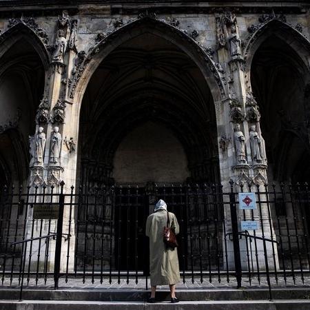 10.abr.2020 - Mulher reza sozinha do lado de fora da igreja Saint-Germain l"Auxerrois, em Paris, na Sexta-Feira Santa - Ian Langsdon/EFE/EPA