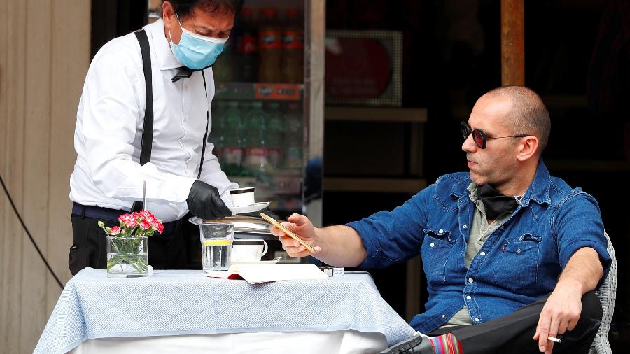 Homem é servido por garçom com máscara de proteção em restaurante de Roma - 