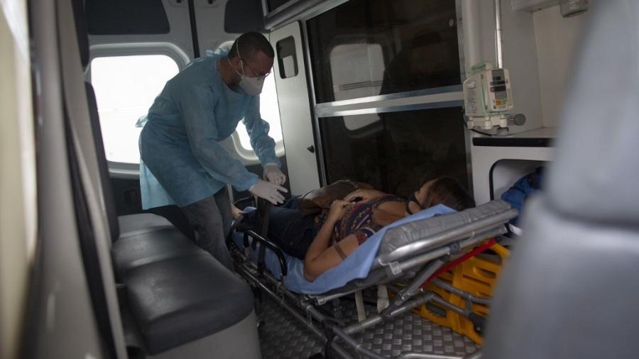 24.mai.2020 - Enfermeiro voluntário Maycon Nogueira prepara paciente com sintomas de covid-19, em ambulância, para transferência até um hospital  - Mauro Pimentel/AFP