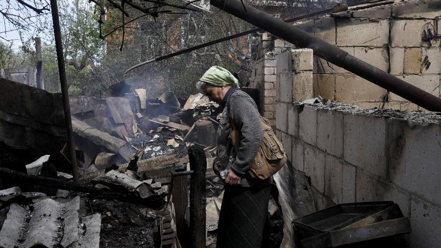 Mulher do lado de fora de sua casa destruída após bombardeio russo na vila de Bezruky, na região de Kharkiv - REUTERS/Ricardo Moraes