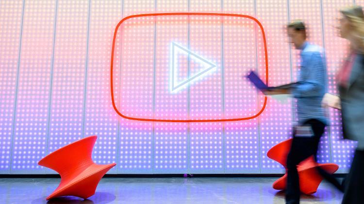 Pessoas caminham em frente ao logotipo do YouTube na sede da empresa em San Bruno, na Califórnia (EUA)
