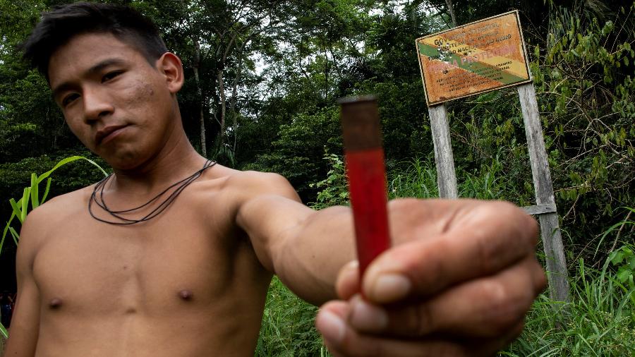 Boatuto, índio do povo Uru-eu-wau-wau, mostra cápsula de munição usada contra placa da Funai que indica os limites da reserva - 31.jan.2019 -  Reuters/Ueslei Marcelino