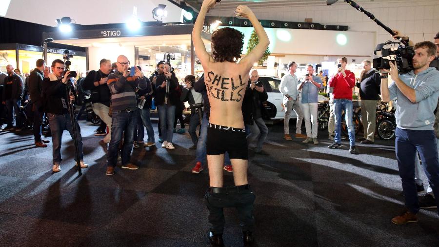 Ativista do Extinction Rebellion mostra as palavras "Shell mata" pintadas em seu corpo no Salão do Automóvel de Bruxelas - François Walschaerts/AFP