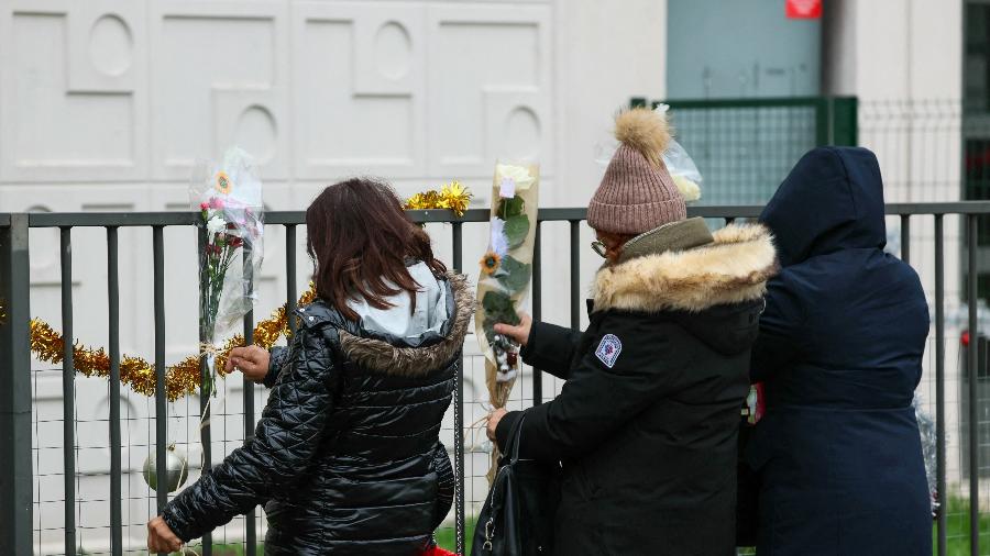 26.dez.2023 - Pessoas depositam flores em frente ao apartamento onde mulher e seus filhos foram mortos, em Meaux, na França