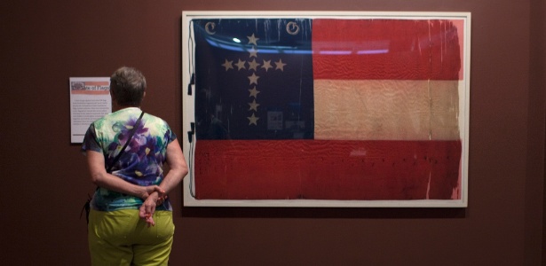 Visitante observa uma bandeira confederada que foi usada por um regimento da infantaria de Kentucky, uma parte da exposição "Cores de Cinza: Consagração e Controvérsia", no Museu dos Confederados, em Virgínia - Khue Bui/The New York Times
